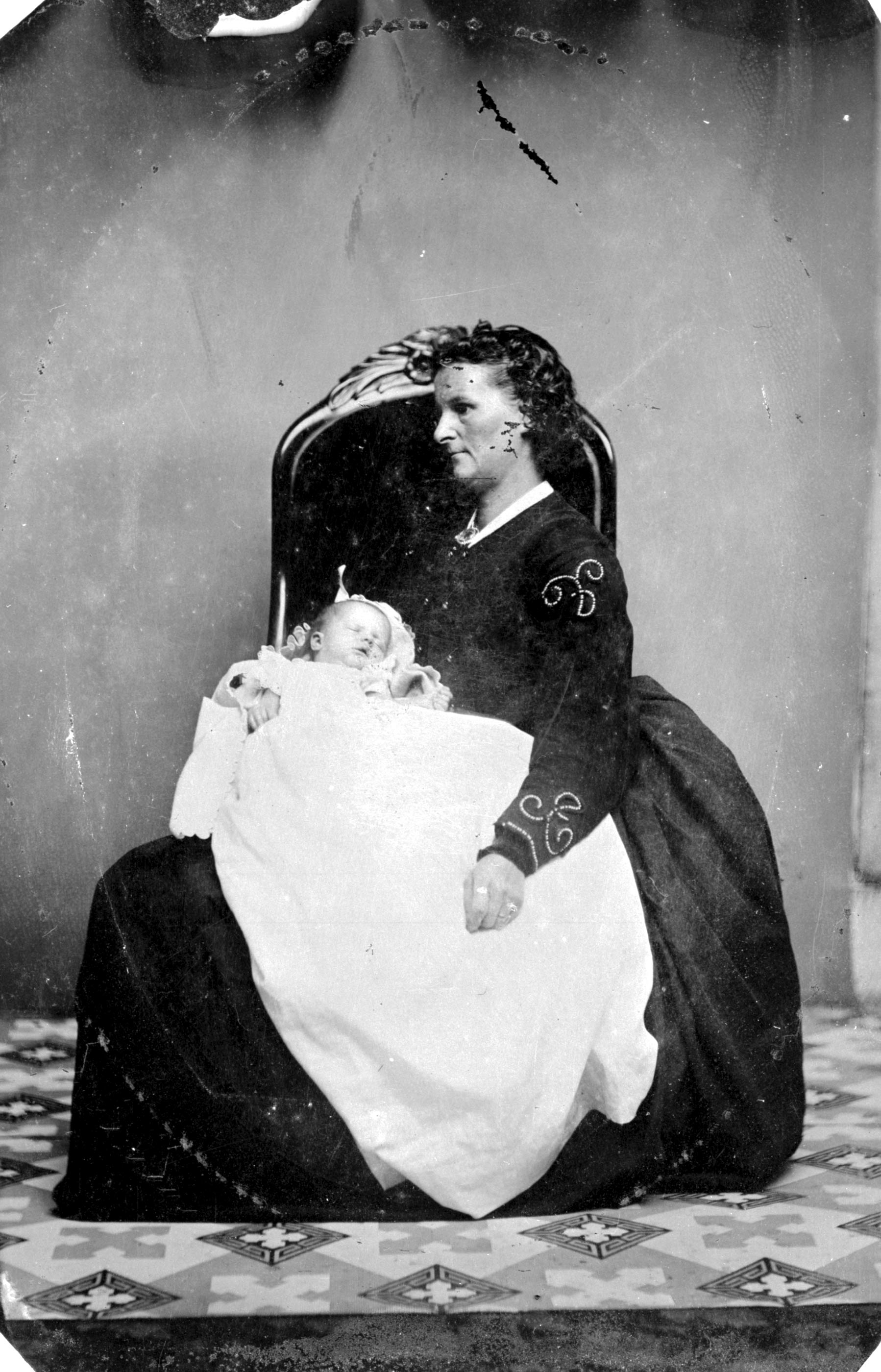 A black and white photo of a woman seated with a baby.